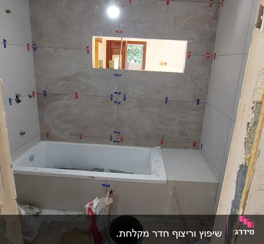חדר אמבטיה בשיפוץ עם אריחים ודלי צבע